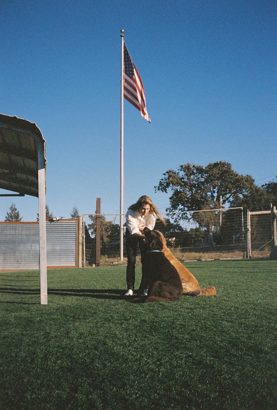 A woman greeting a dog by the flagpole