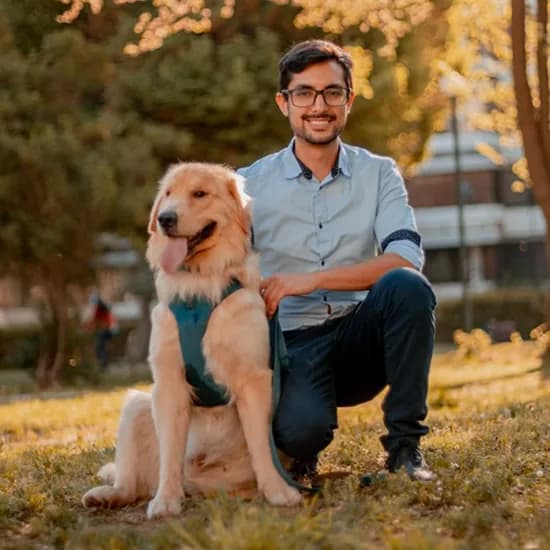 A man crouching beside his golden retriever